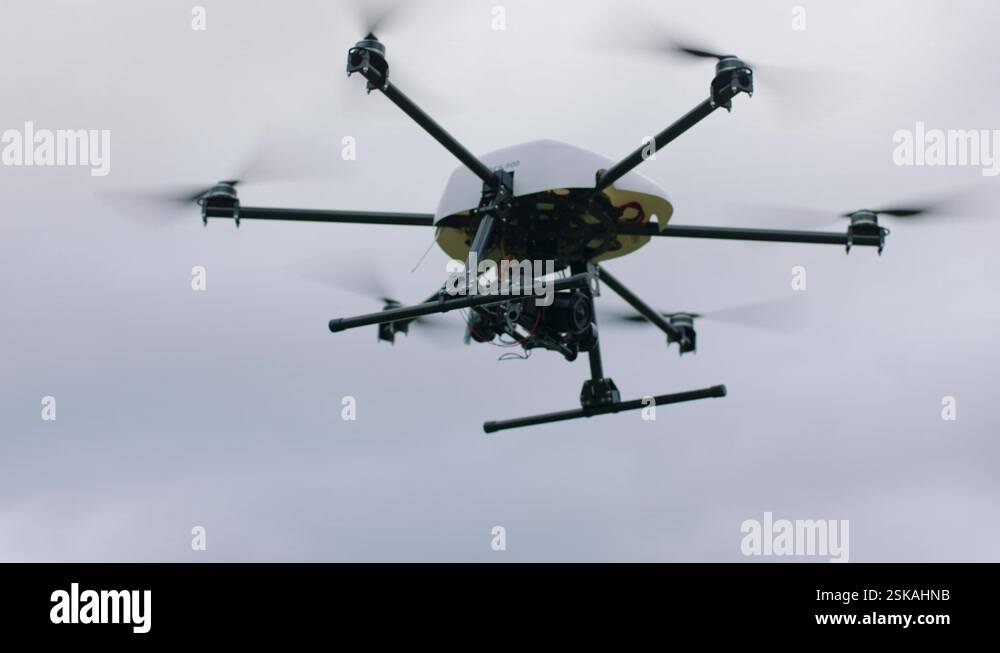 Handheld camera shot of black and yellow drone with six propellers and ...