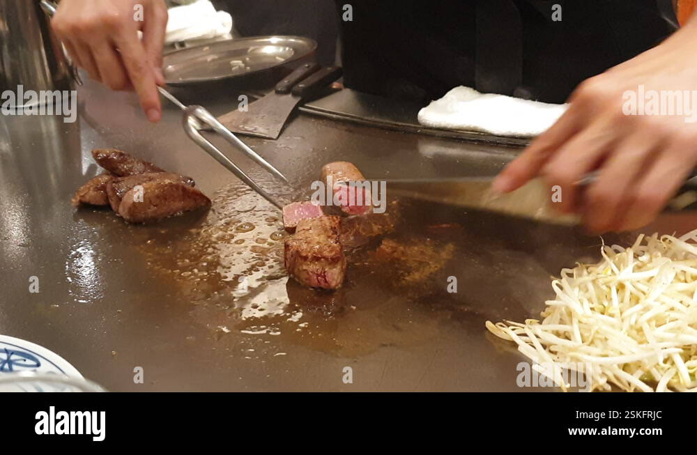 Chef cooking cutting wagyu kobe beef steak on teppanyaki metal plate ...