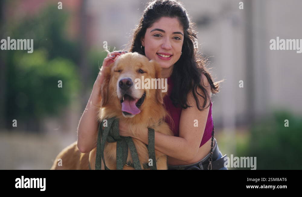 One young woman posing for camera with her Golden Retriever Dog at park ...