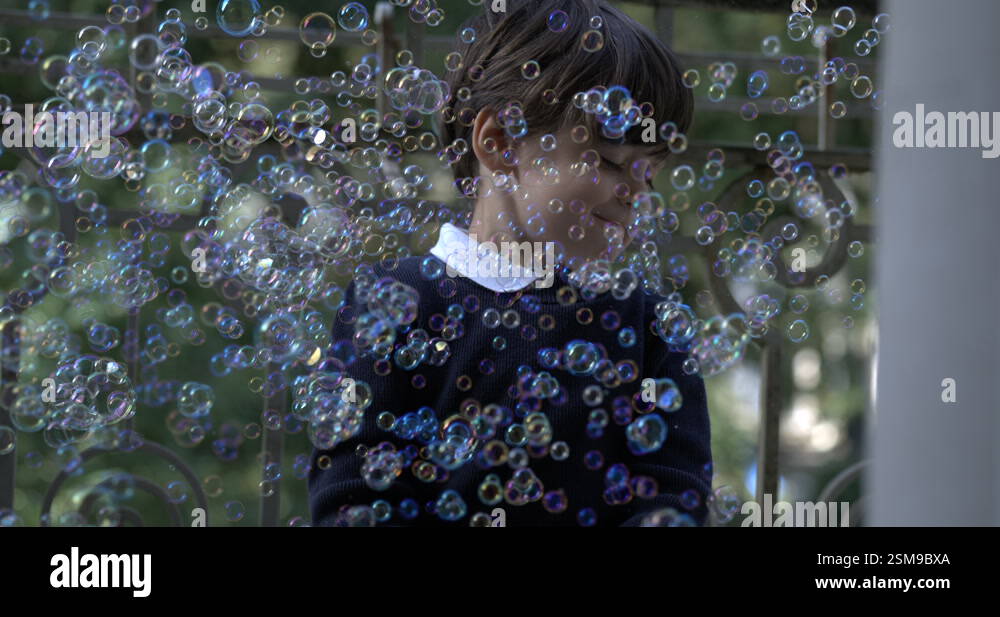 Little boy immersed in thousands of soap bubbles captured in slow ...