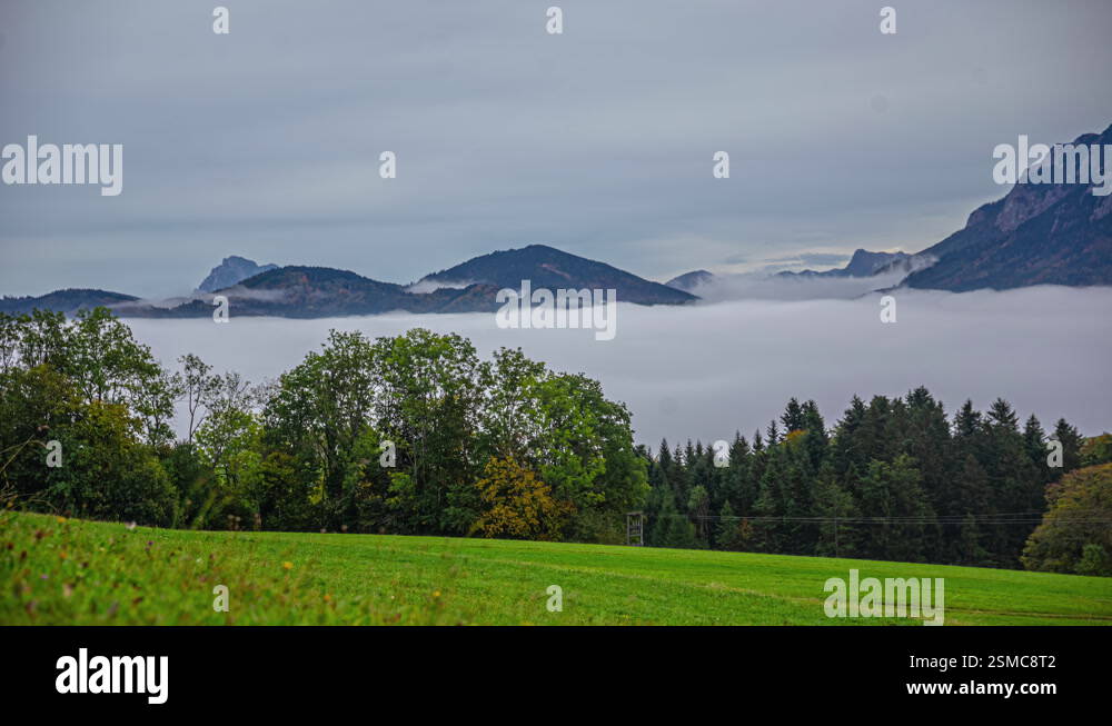 The wavy movements of low hanging clouds in a green alpine valley. Time ...
