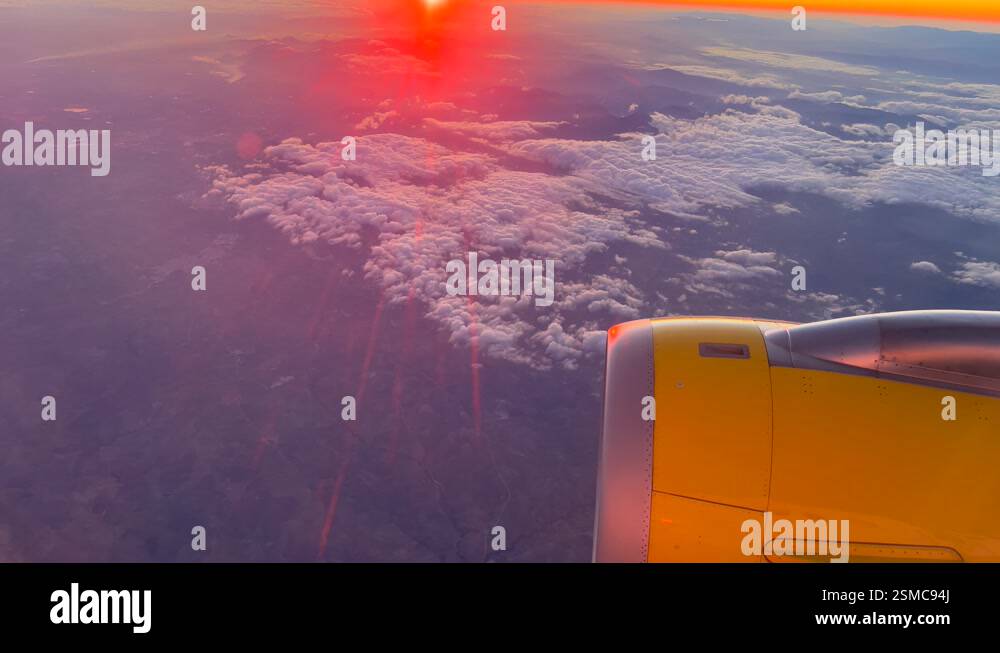 Airplane turbine jet engine flying over clouds with bright red sun ...