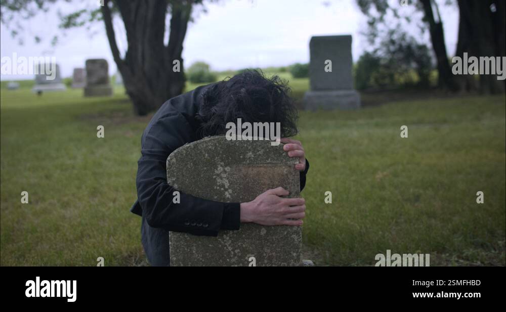 Sad, depressed man hugging tombstone grieving death of family Stock ...