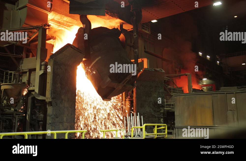 Intense steel mill scene with molten metal being poured from a ladle in ...