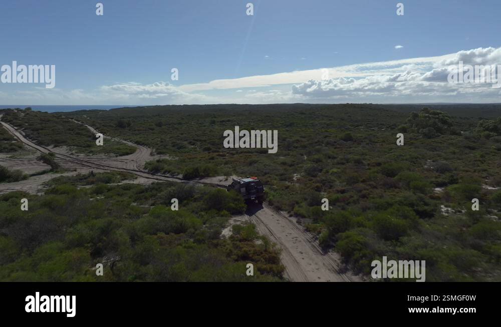 Car driving up a sand dune hill climb on the coast, deep ruts in the ...