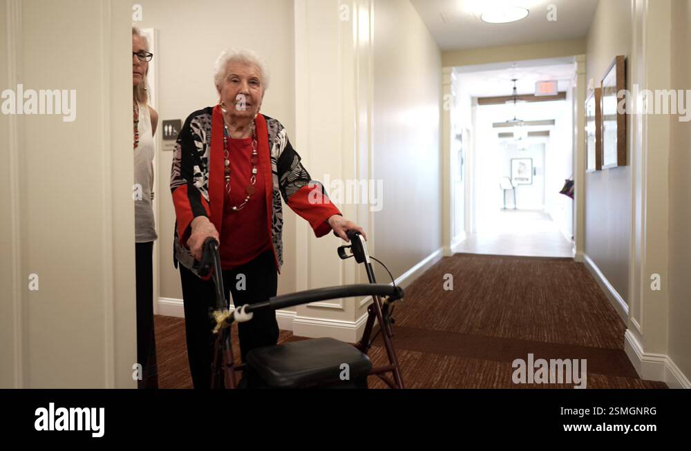 Elderly woman or grandmother using walker to walk with daughter down a ...