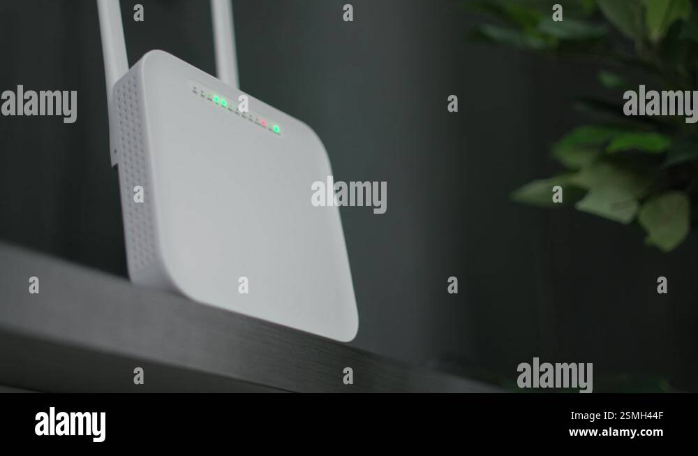 Modern white modem router with a flashing green light hangs on the wall ...