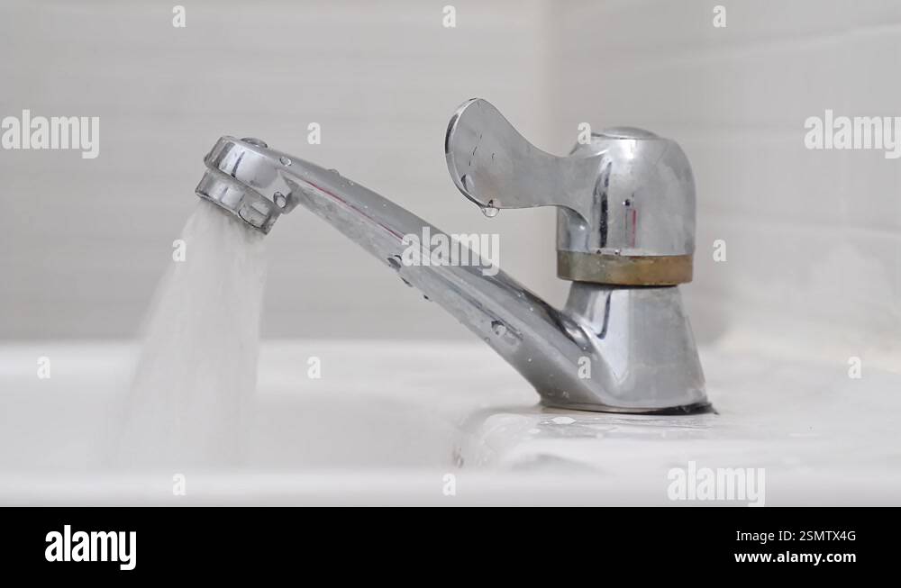 Closeup view of hand turning water tap for pouring water into sink in ...