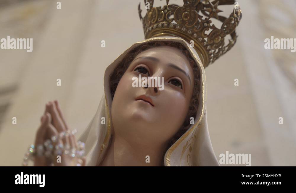 Close up Statue of Virgin Mary wearing a golden crown, hands in prayer ...
