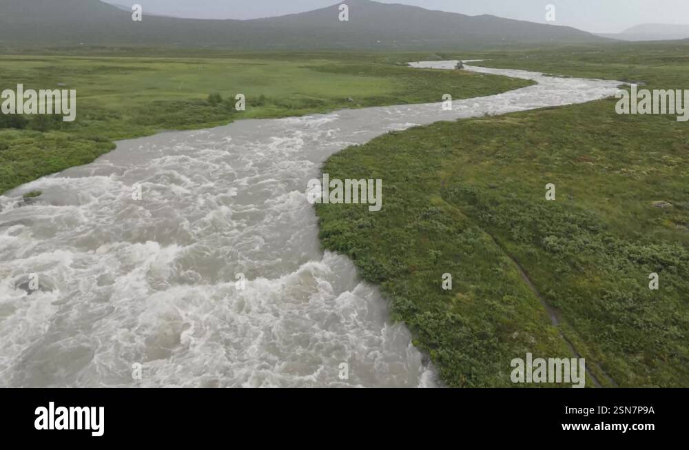 Drone capture of a swiftly moving river on the valley floor, amidst a ...