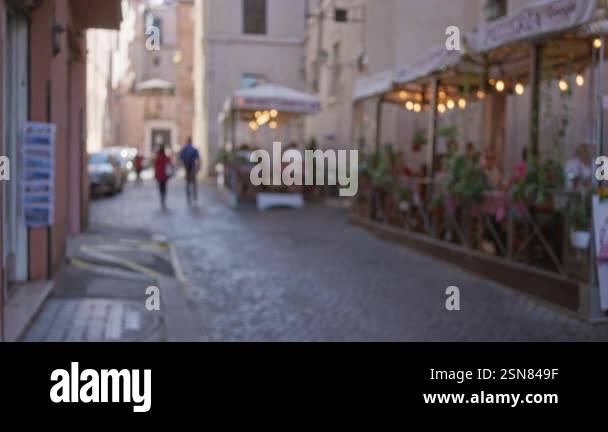 Blurred street scene in rome features people walking on cobblestone and ...