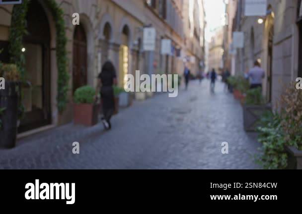Blurred scene of people walking on a cobblestone street in the historic ...