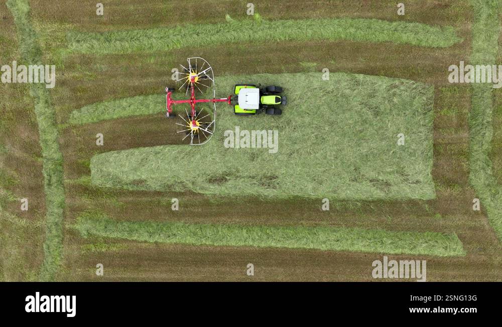 Drone riser view of tractor with twin rotor rake creating windrow of ...