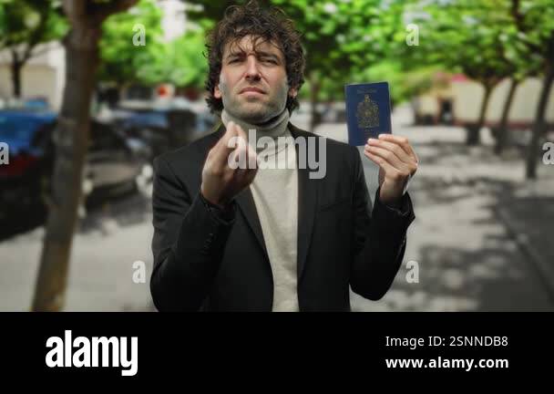 Hispanic man outdoors on a city street displays a canadian passport ...