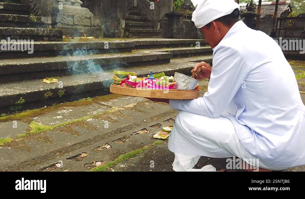 A priest blessing a Temple with water and flowers, ritual at Bali ...