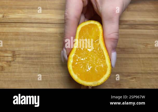 Close up of hands squeezing orange for juice. Human using their hands ...