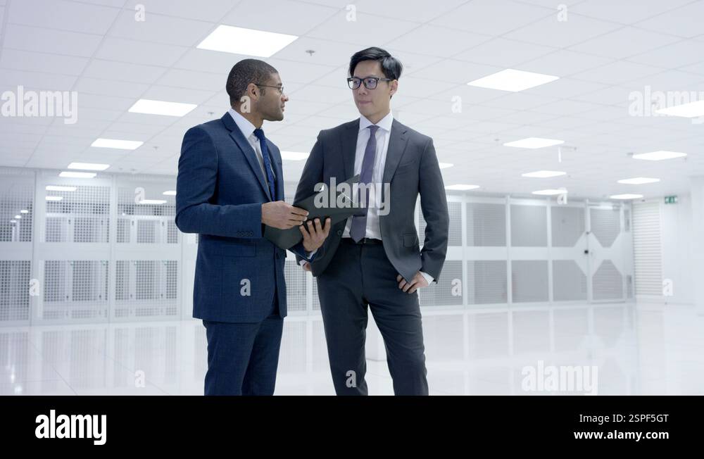 4K Business people looking around large data center with rows of server ...