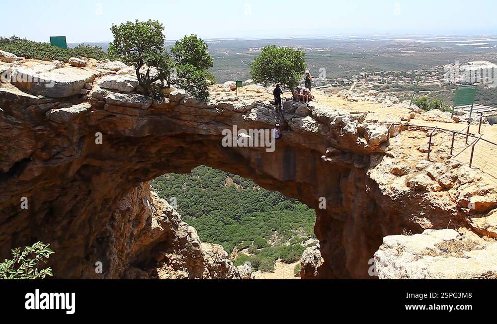 Female rock climber slides on rope in a sunny summer day from a cave ...