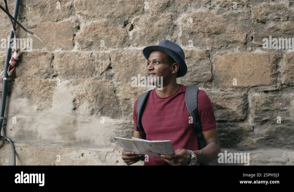 Mixed race tourist man walking and watching paper city map to find ...