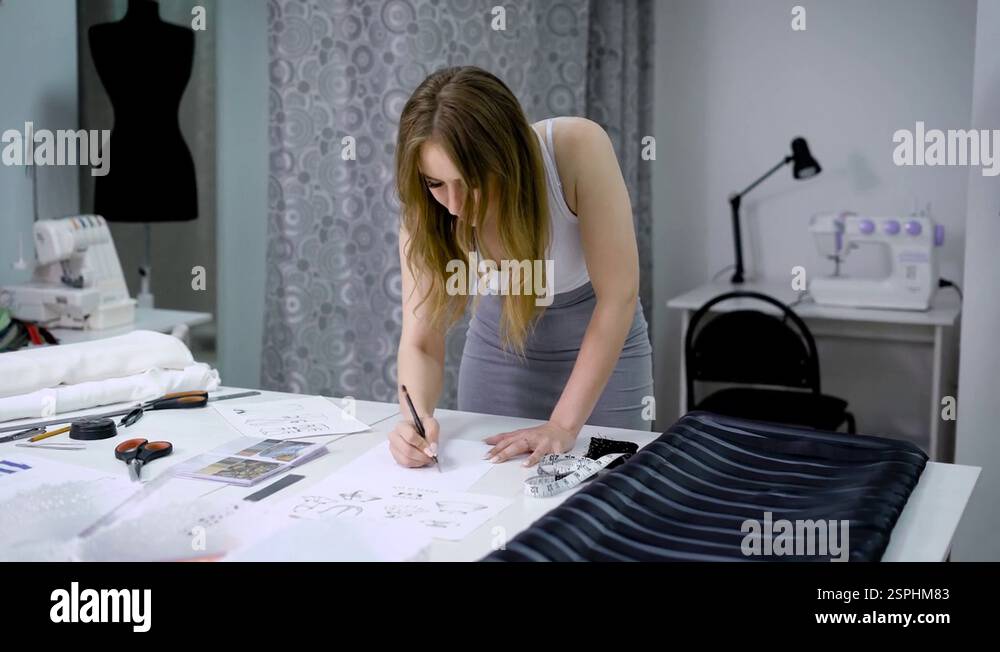 Young girl designing new clothes and drawing sketches in tailor shop ...