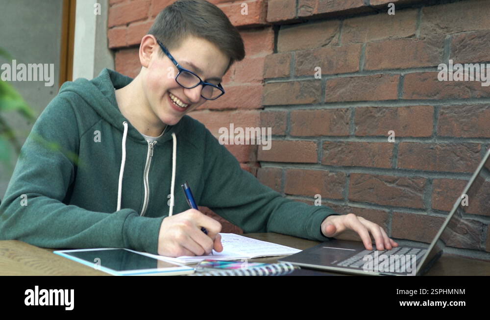 Busy teenager with laptop, smartphone and tablet doing homework by ...