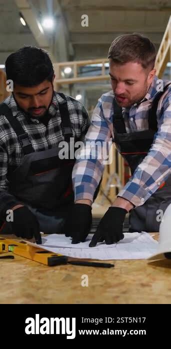 Two engineers analyze construction blueprints at a modular home factory ...
