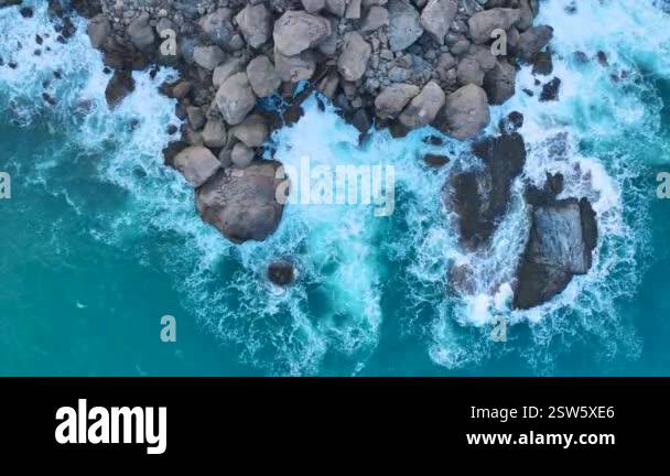 Stormy waves smash into the rocks at dawn, showing the texture and ...