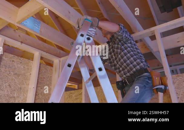 A construction worker is seen carefully installing wooden beams in the ...