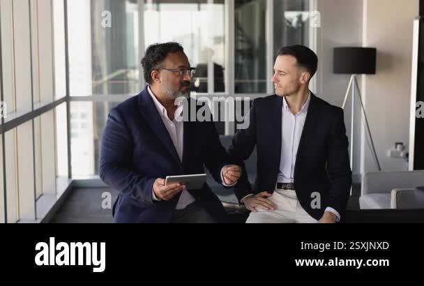 Senior Indian business leader man giving instructions to younger Latin ...
