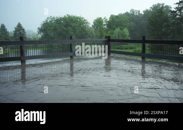 Rain falling on backyard with fancy wooden fence and green park ...