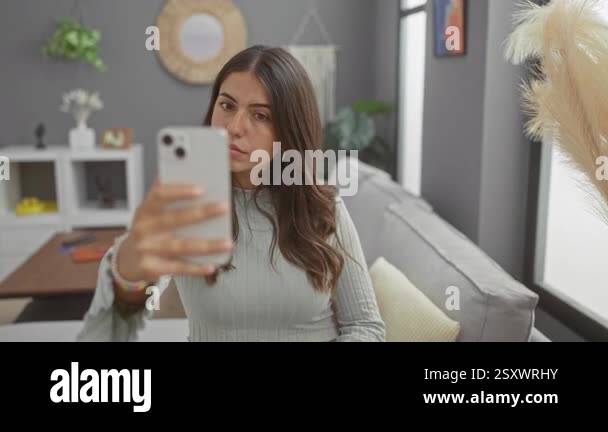 Woman taking selfie with smartphone in modern livingroom featuring gray ...