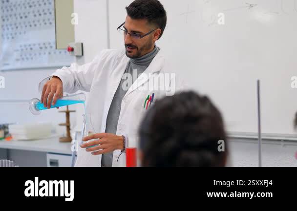 Science teacher performing a chemistry experiment for students, pouring ...