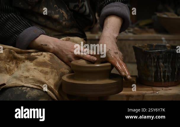 Close-up of a potters hands shaping a clay pot on a spinning pottery ...