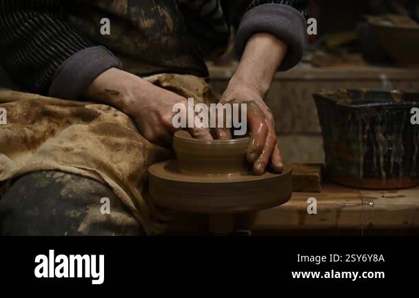 Close-up of a potters hands shaping a clay pot on a spinning pottery ...