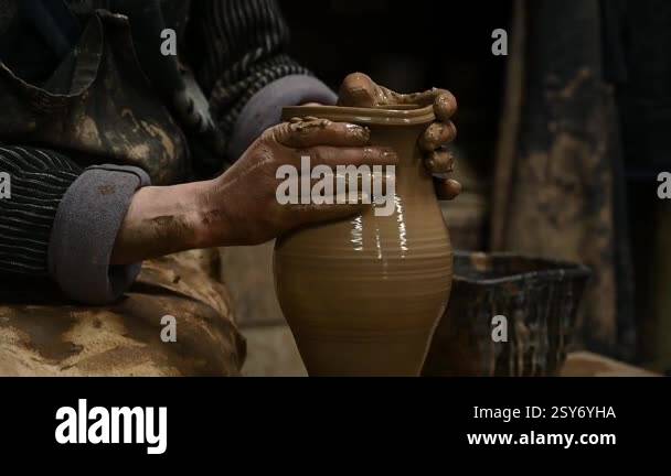 Close-up of a potters hands shaping a clay pot on a spinning pottery ...