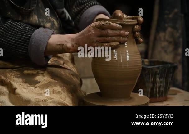 Close-up of a potters hands shaping a clay pot on a spinning pottery ...