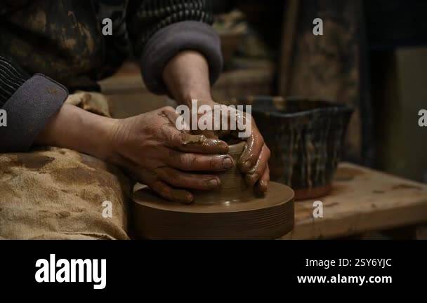 Close-up of a potters hands shaping a clay pot on a spinning pottery ...