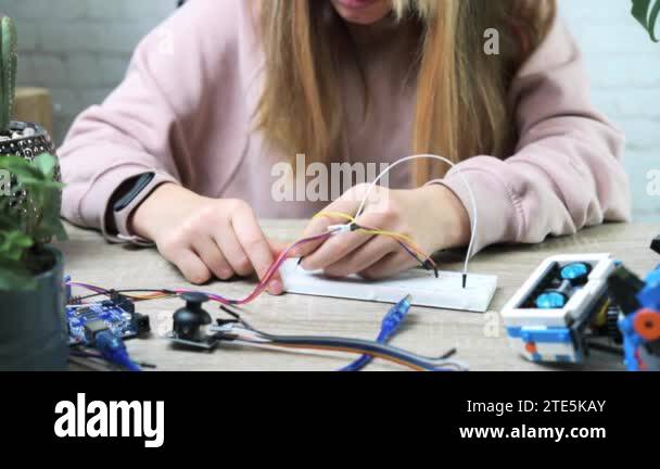 A student girl plugging cables to sensor chips while learning arduino ...