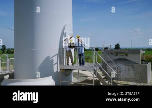Two engineers are standing together discussing wind power projects and ...