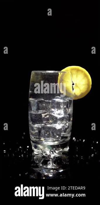 Slow motion splash of an ice cube in a glass of fizzy drink decorated ...