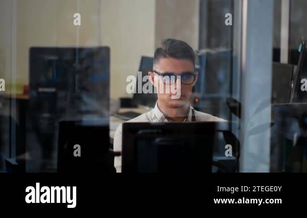 Portrait video filming through the window of a young man in glasses ...