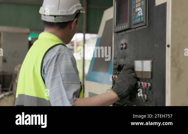 At a manufacturing factory, an industrial engineer operates a control ...