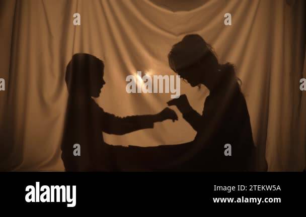 Shadow Rejoicing Silhouettes of woman and boy telling stories using shadow play with ...