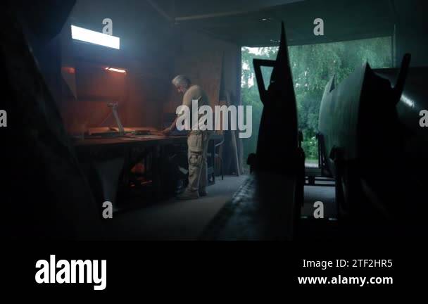 Aged craftsman creates future model of plane in garage. Senior engineer ...