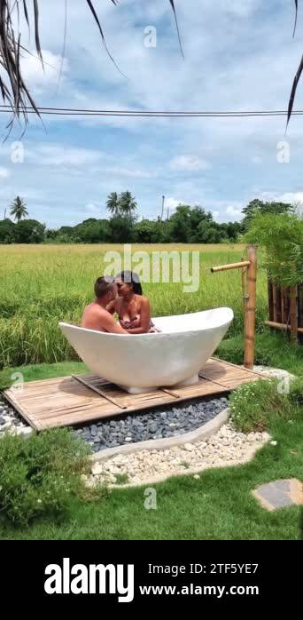 couple men and women in a white bathtub outside looking out over green ...
