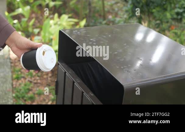 women hand throwing an empty coffee paper cup in the garbage trash or ...