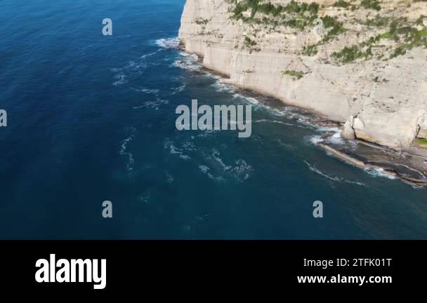 Aerial top view of waves break on rocks in a blue ocean. Sea waves on ...