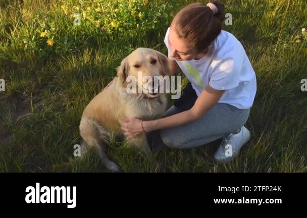 Young woman playing with her dog golden retriever at the park ...