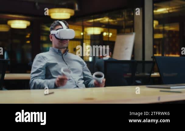 Male office worker using VR headset and wireless controllers, gesturing ...