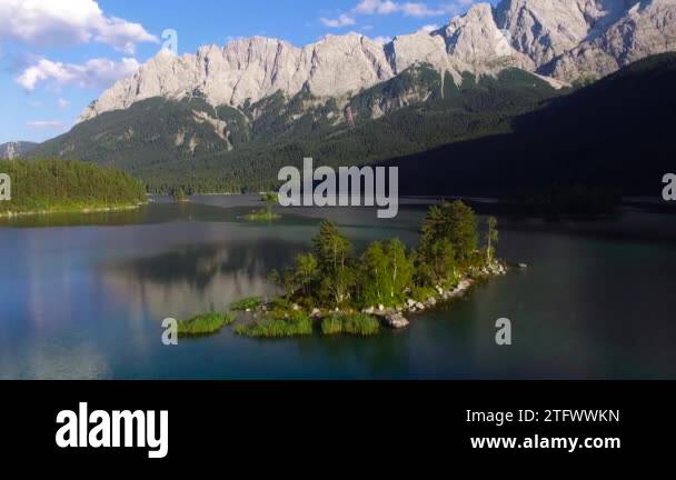 Aerial footage of mountain lake Eibsee beneath Zugspitze peak with ...